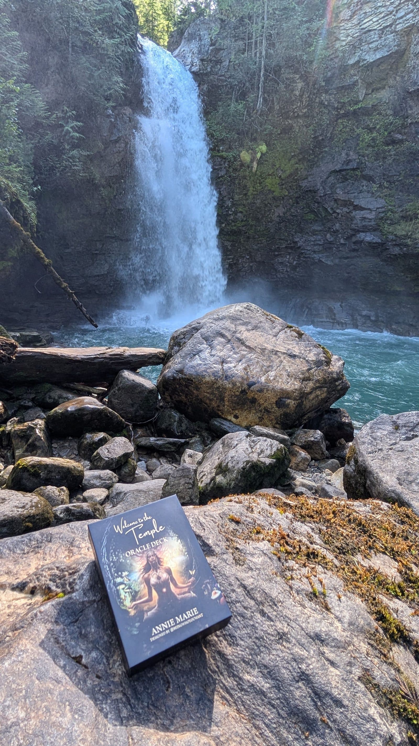 Oracle cards resting on rock beside a waterfall
