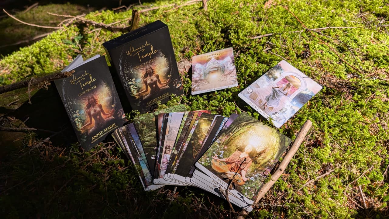 The Welcome to the Temple oracle deck, guidebook and cards spread on moss
